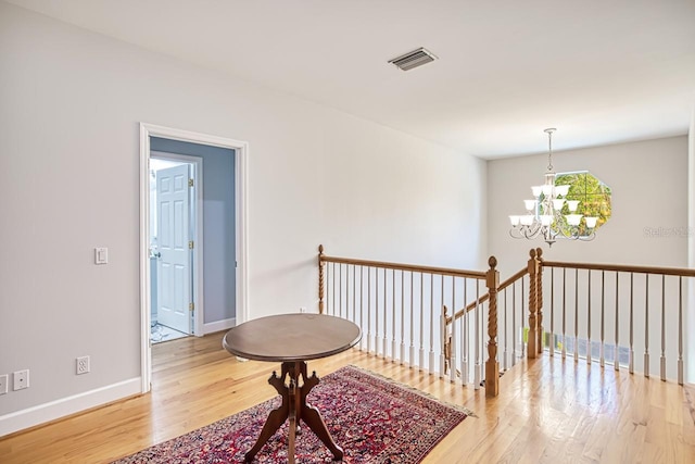 hall featuring hardwood / wood-style floors and an inviting chandelier