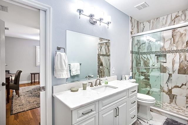 bathroom with hardwood / wood-style flooring, vanity, toilet, and an enclosed shower