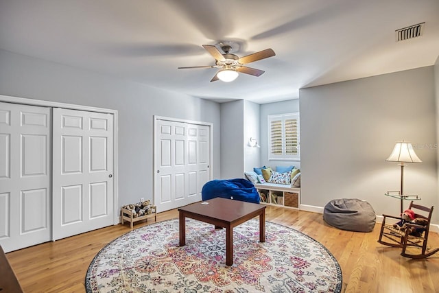 living area featuring wood-type flooring and ceiling fan