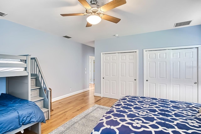 bedroom featuring multiple closets, ceiling fan, and hardwood / wood-style flooring