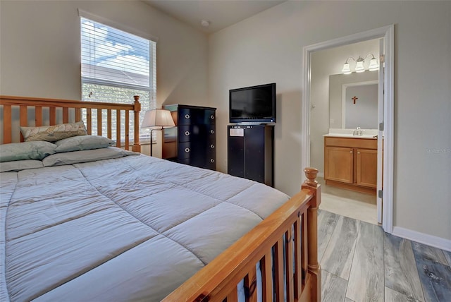 bedroom featuring sink, connected bathroom, and light hardwood / wood-style flooring