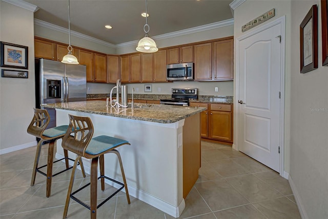 kitchen featuring sink, a kitchen breakfast bar, stainless steel appliances, an island with sink, and decorative light fixtures