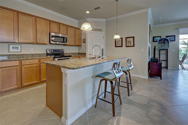 kitchen with appliances with stainless steel finishes, sink, an island with sink, and light tile patterned floors