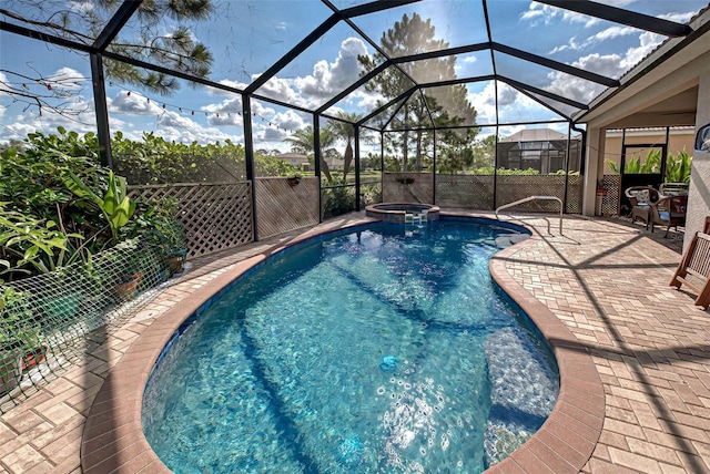 view of pool with an in ground hot tub, glass enclosure, and a patio