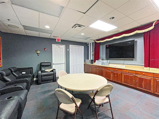 carpeted dining area with a paneled ceiling