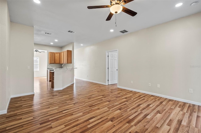 unfurnished living room featuring ceiling fan and light hardwood / wood-style floors