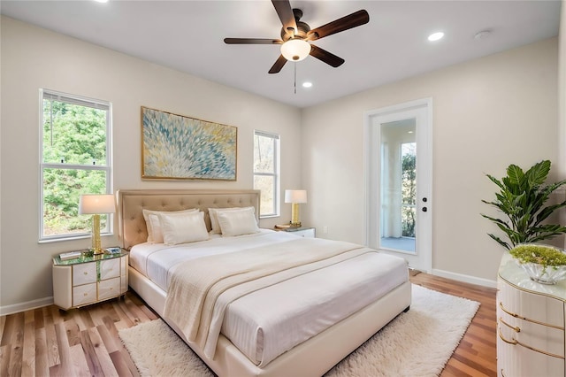 bedroom featuring multiple windows, access to exterior, light hardwood / wood-style flooring, and ceiling fan