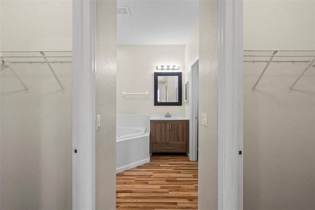 bathroom featuring hardwood / wood-style flooring, vanity, and a washtub