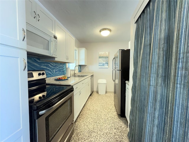 kitchen featuring appliances with stainless steel finishes, light countertops, white cabinets, and a sink