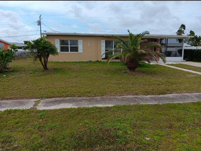 view of front of property featuring stucco siding, a carport, and a front yard