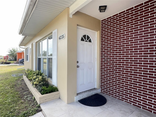 property entrance featuring brick siding and a yard