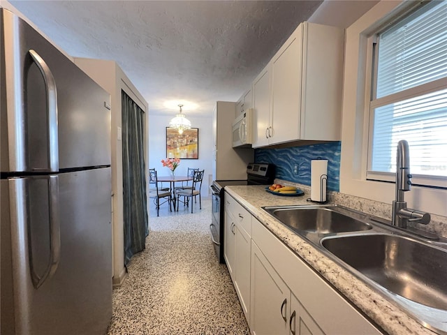 kitchen featuring appliances with stainless steel finishes, white cabinetry, a sink, and a textured ceiling