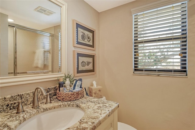 bathroom featuring toilet, a shower stall, visible vents, and vanity