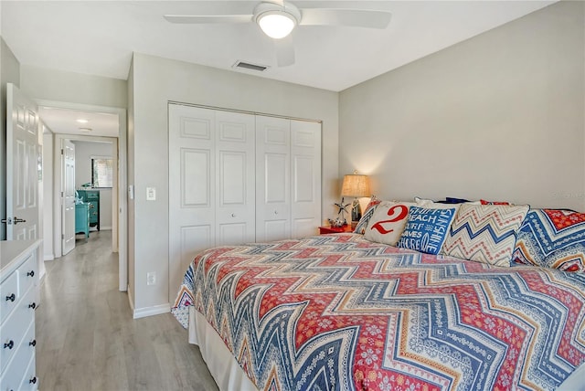 bedroom featuring visible vents, baseboards, a ceiling fan, light wood-style flooring, and a closet