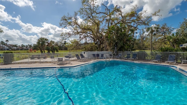 community pool with a patio area and fence