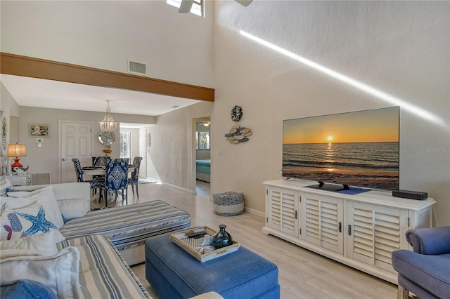 living area featuring a high ceiling, wood finished floors, visible vents, and baseboards