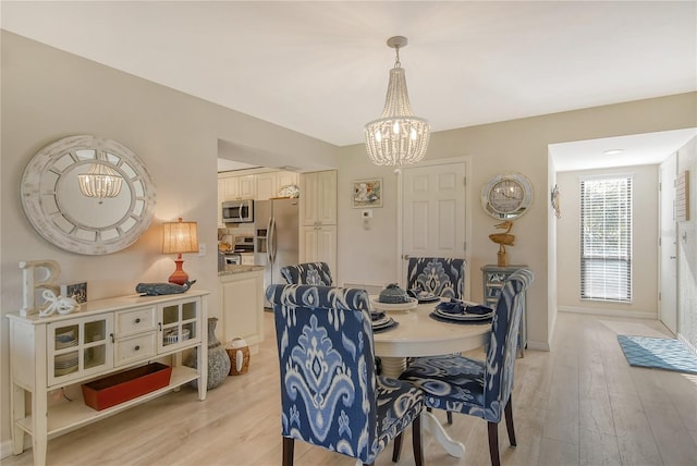 dining area featuring light wood-type flooring, an inviting chandelier, and baseboards