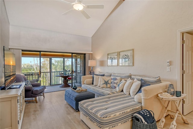 living area with high vaulted ceiling, light wood-type flooring, and a ceiling fan