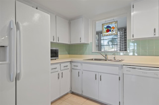 kitchen featuring sink, light tile patterned floors, white cabinets, white appliances, and backsplash