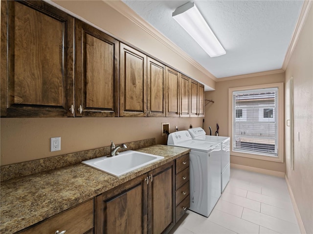 laundry room featuring cabinet space, baseboards, ornamental molding, washing machine and clothes dryer, and a sink