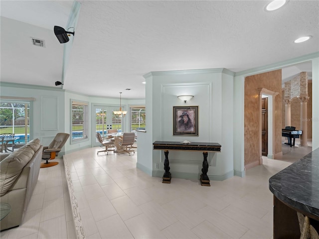 hallway featuring a textured ceiling, a chandelier, visible vents, and baseboards