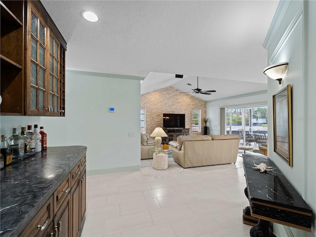 living area with ceiling fan, a textured ceiling, baseboards, vaulted ceiling, and a dry bar