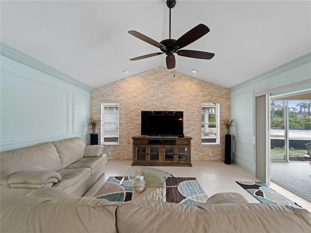 living area featuring light tile patterned floors, lofted ceiling, ceiling fan, crown molding, and a decorative wall