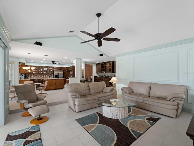 living room with lofted ceiling, light tile patterned flooring, a decorative wall, and ceiling fan with notable chandelier