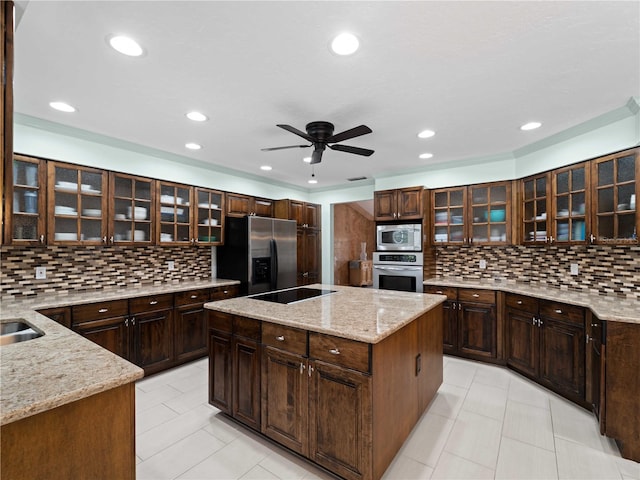 kitchen with a center island, tasteful backsplash, appliances with stainless steel finishes, ceiling fan, and light stone countertops