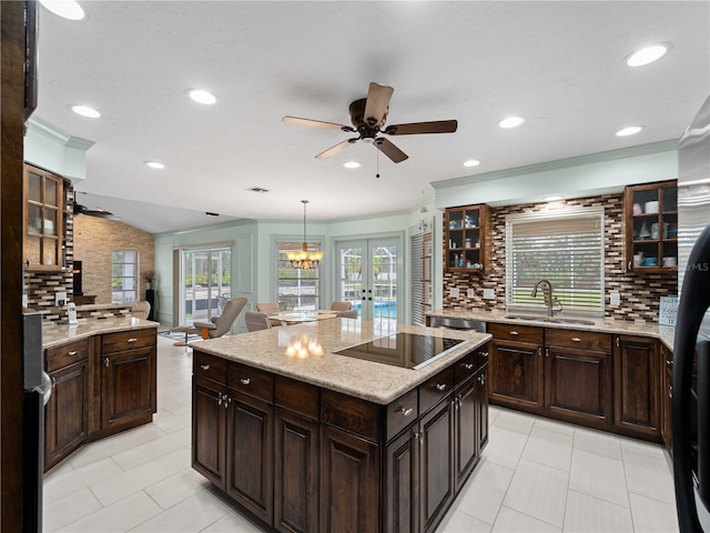 kitchen featuring french doors, decorative backsplash, open floor plan, a sink, and black appliances