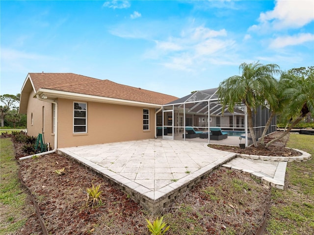 back of house with a shingled roof, an outdoor pool, a lanai, a patio area, and stucco siding