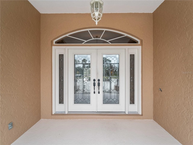 property entrance with stucco siding and french doors