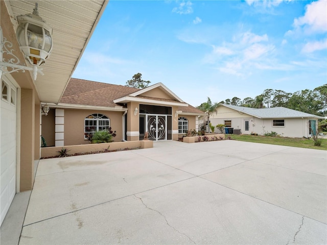 view of front of home with a garage, concrete driveway, a shingled roof, and stucco siding