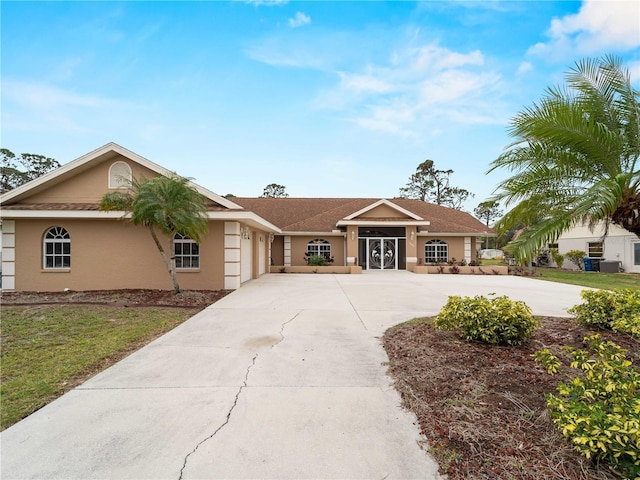 ranch-style house with driveway, an attached garage, and stucco siding