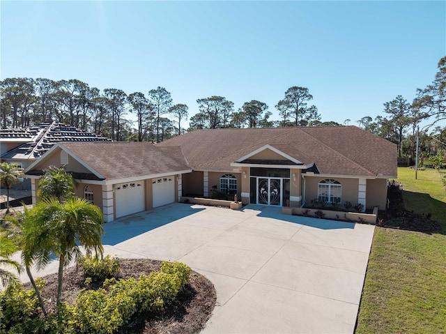 view of front facade featuring an attached garage, driveway, a front lawn, and stucco siding