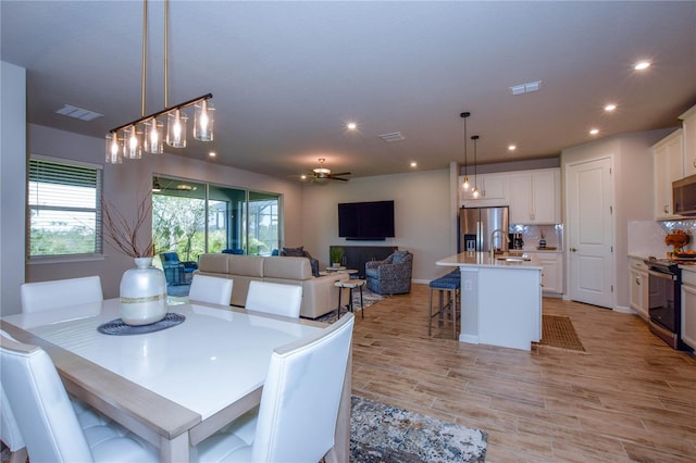 dining room featuring sink, ceiling fan, and light hardwood / wood-style flooring