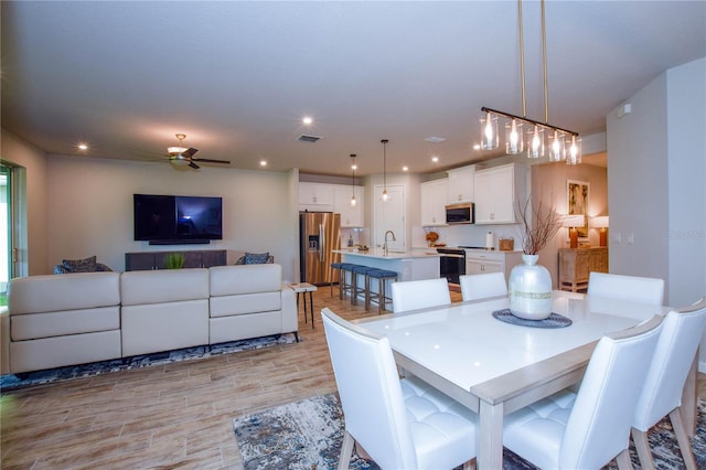 dining space featuring ceiling fan, sink, and light hardwood / wood-style flooring