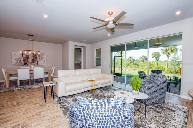 living room with ceiling fan with notable chandelier and light wood-type flooring