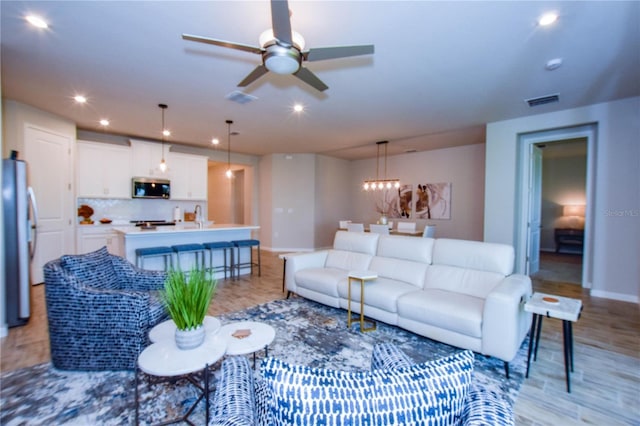 living room with sink, light hardwood / wood-style floors, and ceiling fan