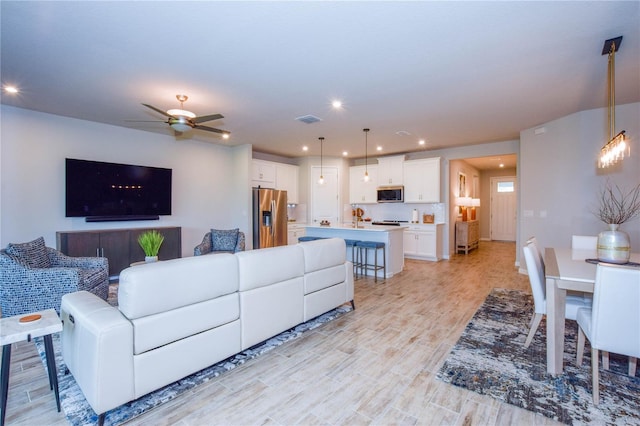 living room featuring ceiling fan and light wood-type flooring