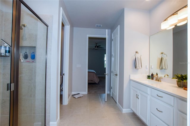 bathroom with a shower with door, vanity, and tile patterned floors