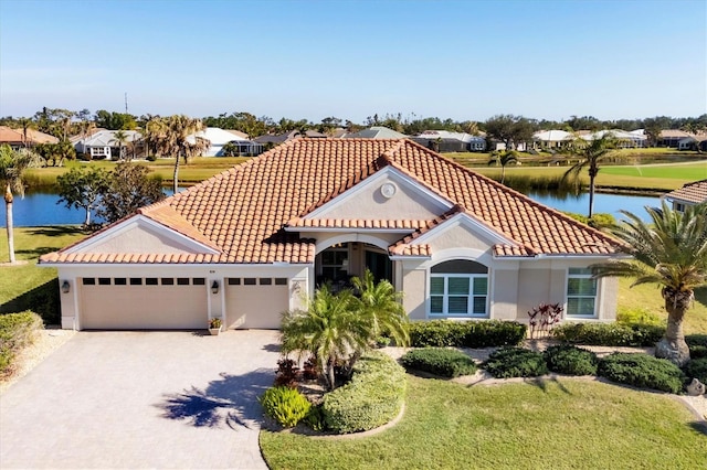 mediterranean / spanish-style home with a garage, a front yard, and a water view