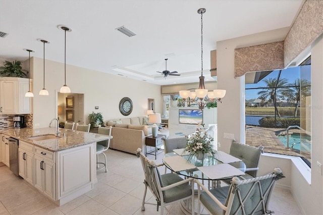 dining room featuring sink, ceiling fan with notable chandelier, a water view, and light tile patterned flooring