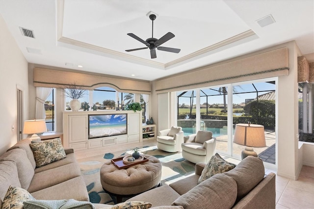 tiled living room featuring crown molding, ceiling fan, and a tray ceiling