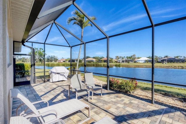 view of patio featuring a grill, a lanai, and a water view