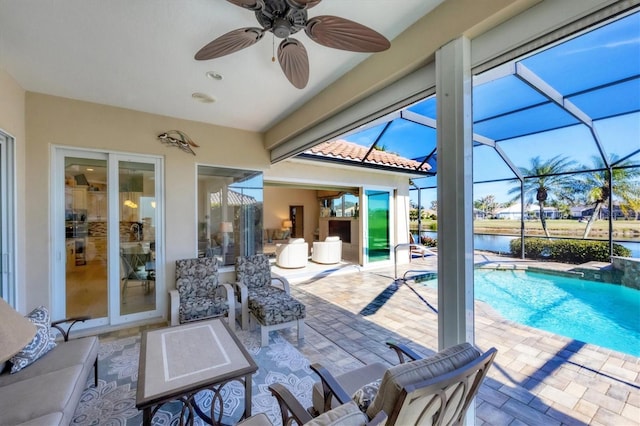 view of patio with a lanai, ceiling fan, and a water view