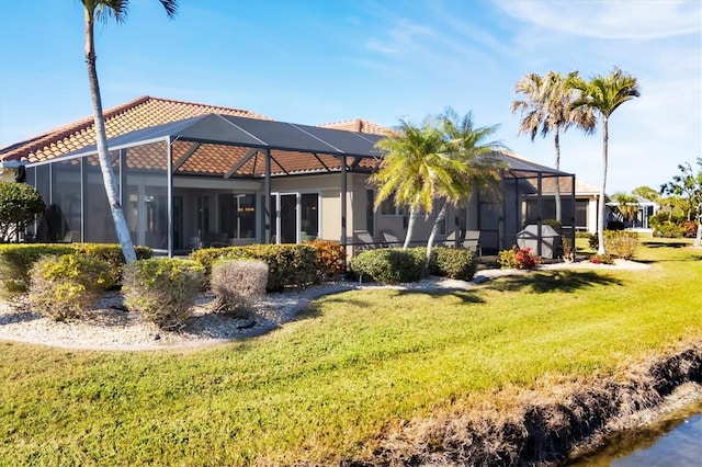 rear view of house featuring a yard and glass enclosure