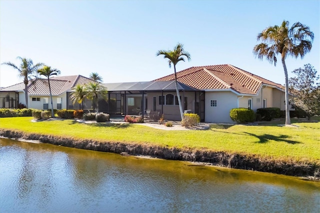 back of house featuring a lawn, a water view, and glass enclosure