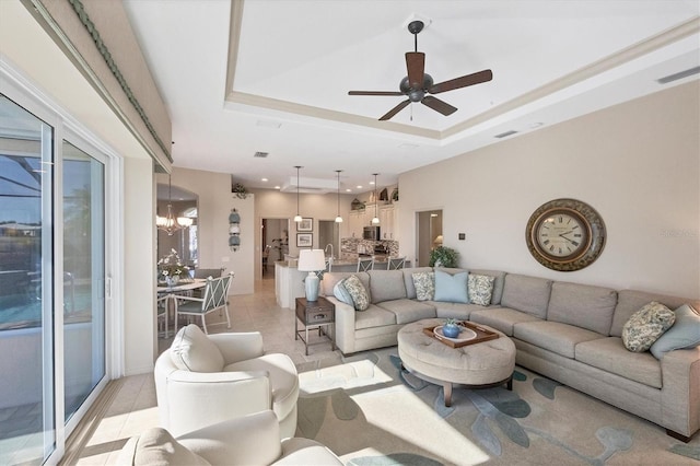 living room with light tile patterned floors, a tray ceiling, and ceiling fan with notable chandelier