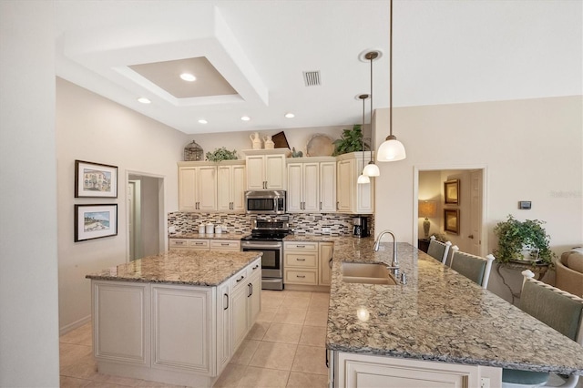 kitchen featuring sink, decorative light fixtures, appliances with stainless steel finishes, a kitchen breakfast bar, and kitchen peninsula